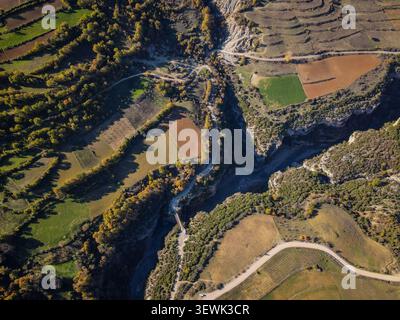 Ein Blick aus der Vogelperspektive fängt den dramatischen Osum Canyon ein, der sich durch eine Landschaft aus verschiedenen landwirtschaftlichen Feldern und üppigen grünen und goldenen Herbstbäumen schlängelt. Di Stockfoto