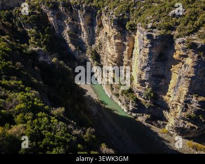 Ein Luftbild fängt den dramatischen Osum Canyon in Albanien ein und zeigt seine steilen, geschichteten Felswände, die von Sonnenlicht beleuchtet und teilweise bedeckt sind Stockfoto
