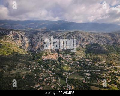 Eine weite Aufnahme aus der Luft fängt das malerische Dorf Moustiers-Sainte-Marie, Frankreich, mit seinen Terrakottadächern am Fuße des imposanten, r Stockfoto