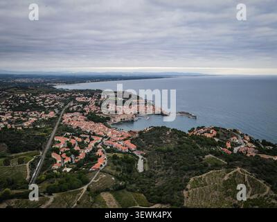 Eine weite Aufnahme aus der Luft zeigt das malerische Küstendorf Collioure, Frankreich, mit seinen roten Ziegeldächern, dem historischen Hafen und dem umliegenden Grün Stockfoto