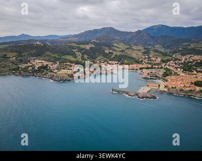 Ein Weitwinkelfoto fängt die malerische Küstenstadt Collioure, Frankreich, ein, eingebettet zwischen dem tiefblauen Mittelmeer und dem üppig grünen bergland Stockfoto