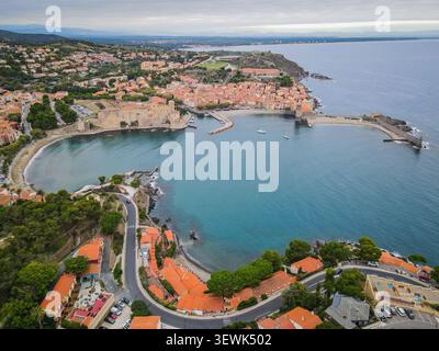Eine weite Luftaufnahme fängt die malerische Küstenstadt Collioure, Frankreich, mit ihrem historischen Königsschloss und Hafen ein. Gebäude mit Orangendach lin Stockfoto