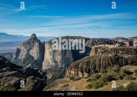 Eine Weitwinkelaufnahme der Region Meteora in Griechenland mit dramatischen Sandsteinsäulen und einem Kloster mit roten Ziegeldächern Stockfoto