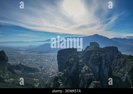 Diese Weitwinkelaufnahme fängt die dramatischen, hoch aufragenden Felssäulen von Meteora im Vordergrund ein, während die Stadt Kalabaka im Tal darunter liegt. Stockfoto