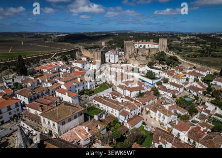 Aus der Vogelperspektive sehen Sie die mittelalterliche Stadt Obidos, ihre weißen Häuser mit Terrakottadächern und die Burg Obidos mit ihren umliegenden Mauern in Portugal Stockfoto