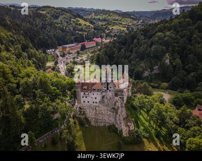 Bran Castle, ein weißes Steingebäude mit roten Dächern und grauen Türmen, steht auf einem Felsvorsprung inmitten grüner Wälder und Hügel in Transsilvanien, römisch Stockfoto