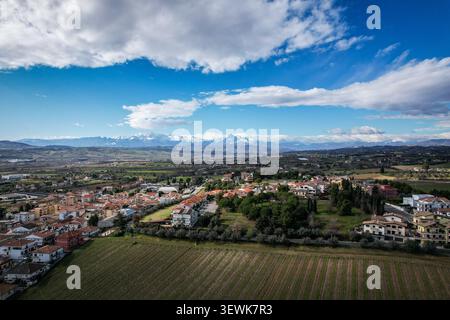 Ein Weitwinkelblick aus der Vogelperspektive zeigt eine Stadt in der Landschaft von San Marino mit Weinbergen im Vordergrund und den verschneiten Apennin am Horizont Stockfoto