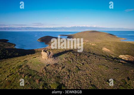 Ein Weitwinkelblick aus der Luft zeigt die Überreste einer alten Steinburg auf einer Halbinsel der Insel Kalem, mit der Ägäis und den fernen Bergen im bac Stockfoto