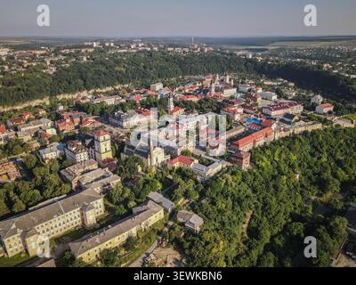 Ein Weitwinkelblick aus der Vogelperspektive fängt die historische Altstadt von Kamianets-Podilskyi ein, eingebettet in die Schlucht des Smotrych River. Gebäude mit rotem Dach, Kirchen, Stockfoto