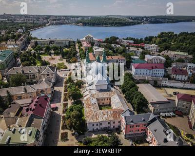 Aus der Vogelperspektive sehen Sie die Dormition Cathedral und den Ternopil See, umgeben von städtischen Gebäuden und Grünflächen in Ternopil, Ukraine. Dieses Bild ist eine Idee Stockfoto
