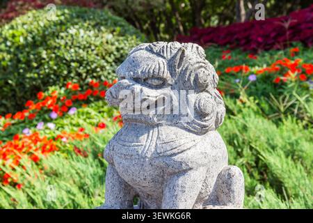 Steinlöwe vor Blumen in Xian, China Stockfoto