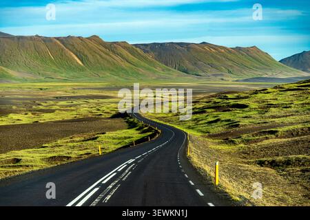 Malerischer Blick auf die leere Asphaltring Road, die sich durch moosige Vulkanfelder und Berge in der Nähe der Region Myvatn in Nordisland schlängelt. Stockfoto