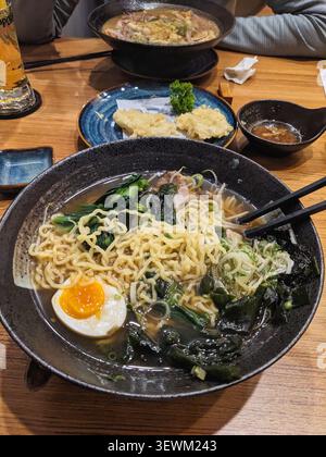 Eine köstliche Schüssel vietnamesischer Pho mit Nudeln, Ei und Gemüse, serviert mit Tempura und Dip-Sauce Stockfoto