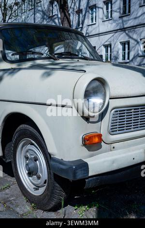 Nahaufnahme des vorderen Abschnitts eines klassischen Trabant 601 (Trabi) mit seinem charakteristischen runden Scheinwerfer, der auf einer Berliner Wohnstraße geparkt ist. Stockfoto