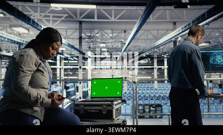 Das Engineering-Team des Rechenzentrums verwendet einen Laptop mit isoliertem Bildschirm in einem Serverraum für die editierbare KI-Infrastruktur. Stockfoto