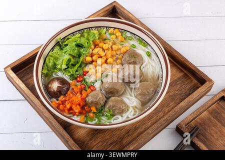 Chinesische Reisnudeln Suppe mit Rindfleischbällchen und Gemüse in Holztablett Stockfoto
