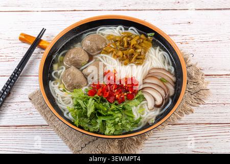 Chinesische Reisnudeln Suppe mit Rindfleischbällchen und Gemüse in Holztablett Stockfoto