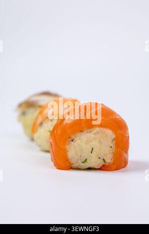 Eine Reihe von drei verschiedenen Gourmet-Sushi-Bällchen mit Lachsen, Garnelen und Aalen wird in Nahaufnahme auf einem nahtlosen weißen Hintergrund gedreht Stockfoto