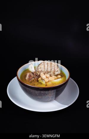 Traditionelle herzhafte Fleischbällchensuppe mit Kichererbsen in dunkler Keramikschale auf schwarzem Hintergrund. Stockfoto