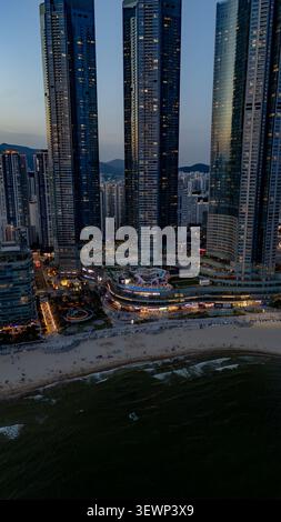 Busan, Südkorea - 24. Juni 2026: Aus der Vogelperspektive auf den Haeundae Beach mit den hohen Wolkenkratzern des LCT-Komplexes, beleuchtet in der Abenddämmerung mit der sa Stockfoto