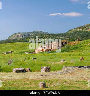 Ein malerischer Blick auf die antiken römischen Theaterruinen in den grünen Hügeln von Hierapolis, Pamukkale, Türkei, unter einem klaren blauen Himmel. Stockfoto