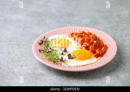 Kontinentales Frühstück: Eier, Mikrogemüse und Bohnen in Tomatensauce auf einem Teller auf dem Tisch. Gesundes Frühstück Stockfoto