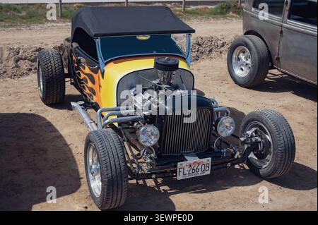 Vorderansicht eines modifizierten schwarzen Ford-Modells 1926 Ein Roadster-Hot Rod mit lackierten Flammen und freiliegendem V6-Motor, der im Freien geparkt ist. Stockfoto