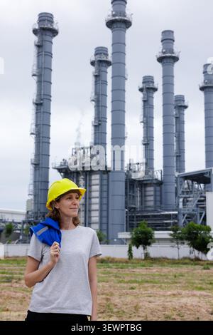 Eine professionelle Ingenieurin steht draußen vor einem modernen Industriekraftwerk. Stockfoto