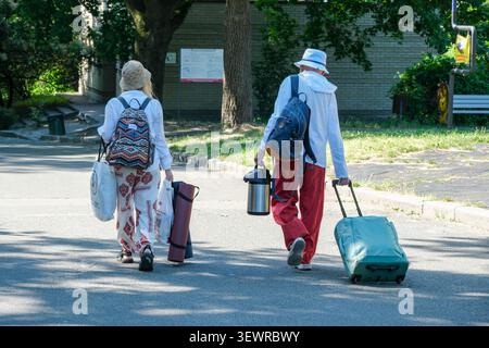 KIEW, UKRAINE - 28. JUNI 2026: Zwei Besucher mit Gepäck, Rucksäcken, Campingausrüstung und einem Rollkoffer, während sie durch M. M. Gryschko Natio spazieren Stockfoto