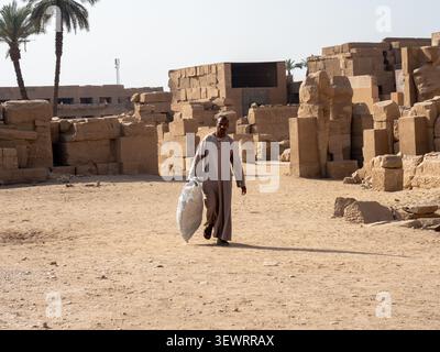 Ägyptischer Mann in traditioneller Kleidung, der durch die antiken Tempelruinen von karnak spaziert Stockfoto