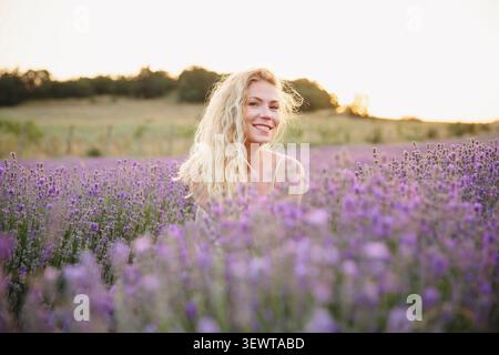 Fröhliches Frauenporträt auf einem Lavendelfeld bei Sonnenuntergang natürliche Schönheit Stockfoto