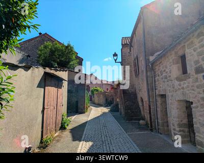 Eine enge Straße in einem alten Steindorf mit traditionellen Steinhäusern mit Holzläden und in La Cavalerie, Frankreich Stockfoto
