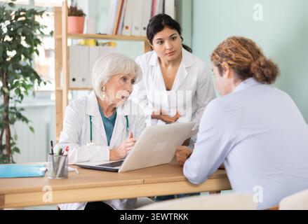 Zwei Ärztinnen erklären dem männlichen Patienten diagnostische Ergebnisse Stockfoto