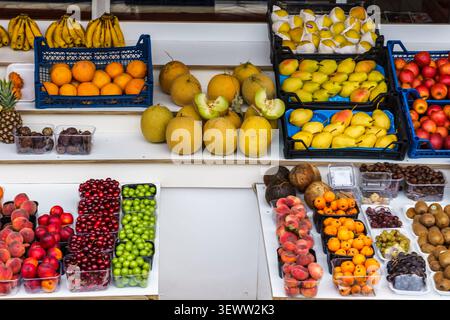 Verschiedene frische Früchte wie Bananen, Orangen, Birnen und Äpfel sind in Körben an einem Marktstand angeordnet und bieten lebendige Farben und Vielfalt Stockfoto