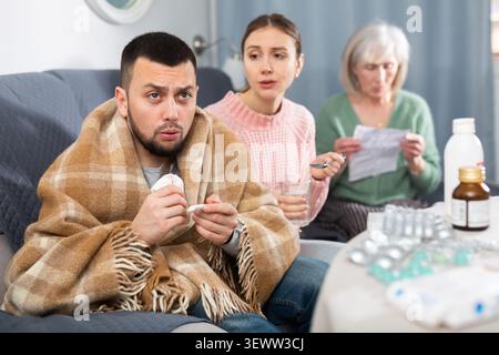 Kranker Mann, der mit Frau und Mutter sitzt Stockfoto