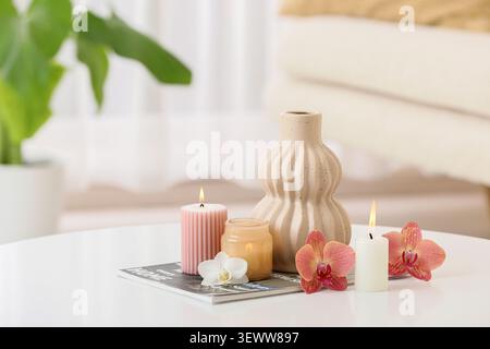 Dekorative Kerzen und Orchideen auf dem Tisch mit Keramikvase Stockfoto