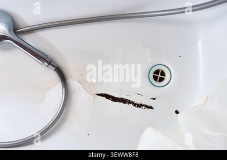Nahaufnahme einer beschädigten weißen Badewanne mit gerissener Emaille, Metallkorrosion und dunklen Rostflecken Stockfoto