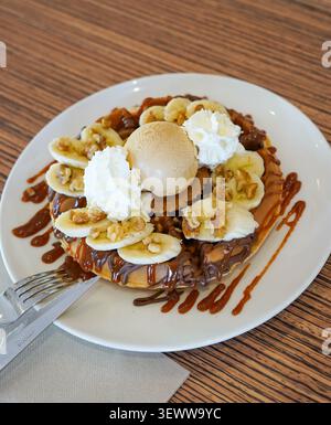 Waffel mit Banane, Walnüssen, Schokoladensoße, Karamell und Eis Stockfoto
