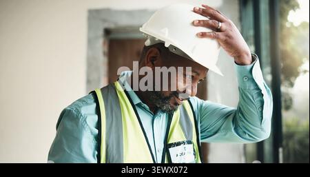 Helm, Konstruktion oder schwarzer Mann im Gebäude zur Inspektion, Bewertung oder Überprüfung der Sicherheitskonformität. Bauingenieur, Architekt oder reife Person Stockfoto