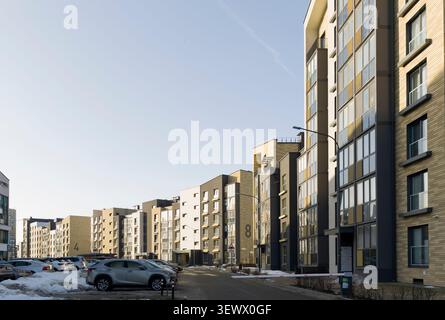 Minsk Weißrussland 8. März 2026 Moderne Wohnanlage, Wohnhäuser, Wohnblocks, Landschaft mit blauem Himmel, Autos Stockfoto