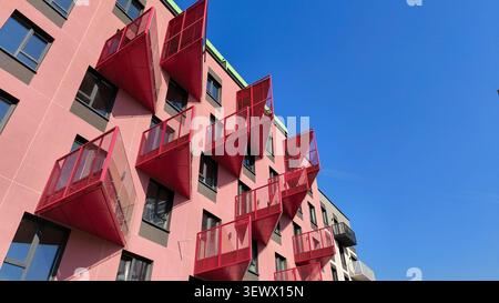 Gebäudefassade mit dreieckigen Balkonen in kräftigen Farben. Moderne Architektur mit geometrischen Formen, die ein dynamisches Außenmuster erzeugen. Städtisch Stockfoto