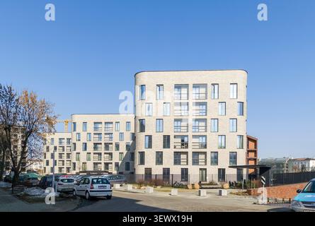 Minsk Weißrussland März 30 2026 an der Straße erheben sich luxuriöse Wohngebäude mit geparkten Autos. Der moderne Apartmentkomplex zeigt gehobene städtische Wohnumgebung Stockfoto