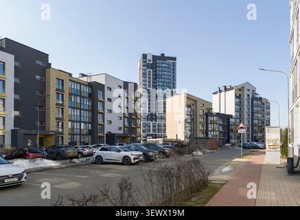 Minsk Weißrussland März 30 2026 Stadtstraße mit geparkten Autos in der Nähe moderner Wohngebäude. Fahrzeuge säumen die Straße neben modernen Apartments in der Stadt Stockfoto