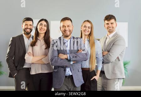 Erfolgreiches junges Business-Team, das mit überkreuzten Armen im Büro steht und in die Kamera blickt. Stockfoto