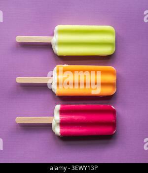 Drei bunte Eispops auf einem violetten Hintergrund Stockfoto