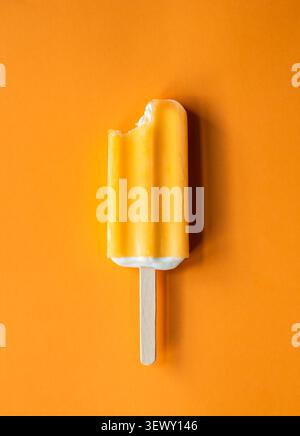 Orangeneis-Bar mit einem Happen, der auf orangefarbenem Hintergrund eingenommen wurde. Stockfoto