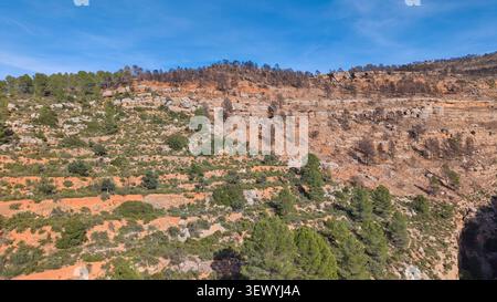 Luftaufnahme von trockenen mediterranen Berghängen mit Terrassengelände, felsigen Klippen und grünen Bäumen in Spanien. Stockfoto