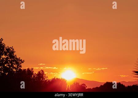 Die untergehende Sonne sinkt hinter dem Berg. Stockfoto