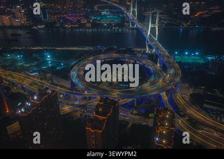 Luftaufnahme der Nanpu-Brücke bei Nacht, mit der beleuchteten Spiralkreuzung und Ampelpfaden über dem Huangpu-Fluss in Shanghai, Shanghai Stockfoto