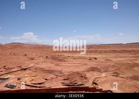Der weite, trockene Wüstenhorizont, der die Provinz Ouarzazate in Marokko umgibt, erstreckt sich majestätisch unter einem blauen Himmel, der von schroffen Wolken gesäumt ist Stockfoto